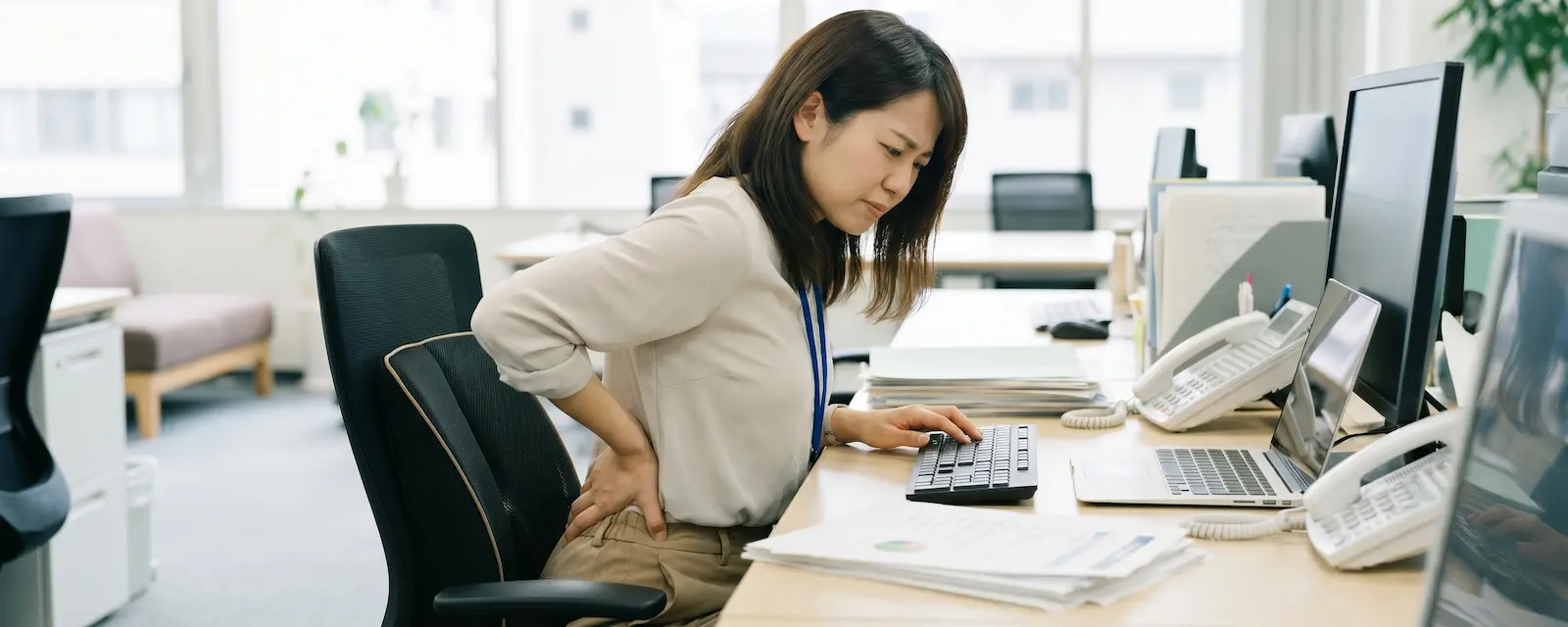 デスクワークで腰痛に悩む女性のイメージ